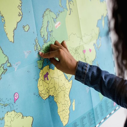 A child is pointing to the UK on a map of the world