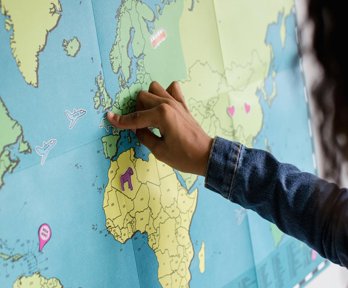 A child is pointing to the UK on a map of the world