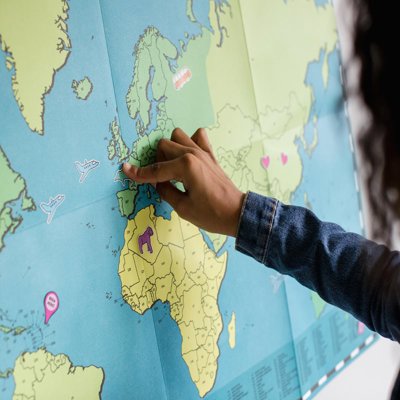 A child is pointing to the UK on a map of the world